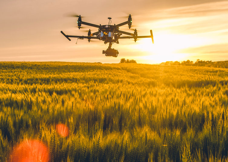Drone technology in action: An aerial drone flying over a field at sunset