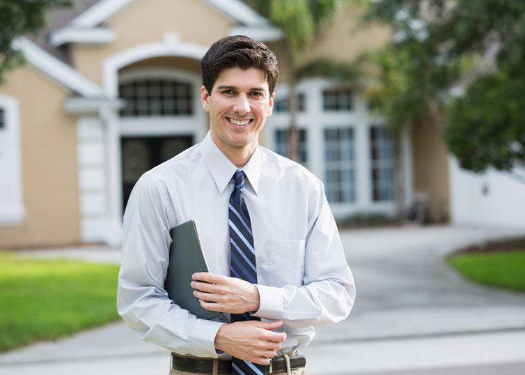 Real estate appraiser who specializes in appraising luxury homes standing outside a high-end home