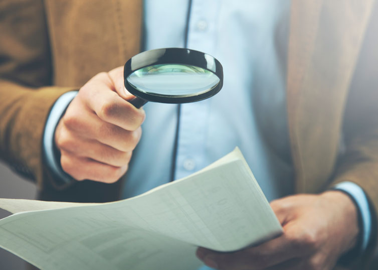 Real estate appraiser analyzing an appraisal report with a magnifying glass